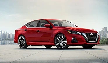2023 Nissan Altima in red with city in background illustrating last year's 2022 model in Bennington Nissan in Bennington VT
